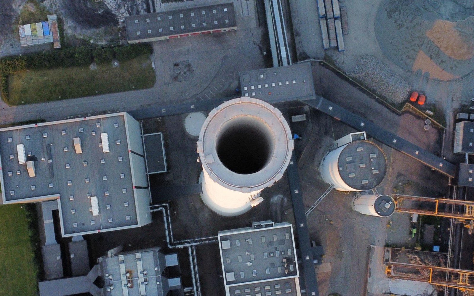Aerial view of a factory chimney and industrial buildings with storage silos and yard