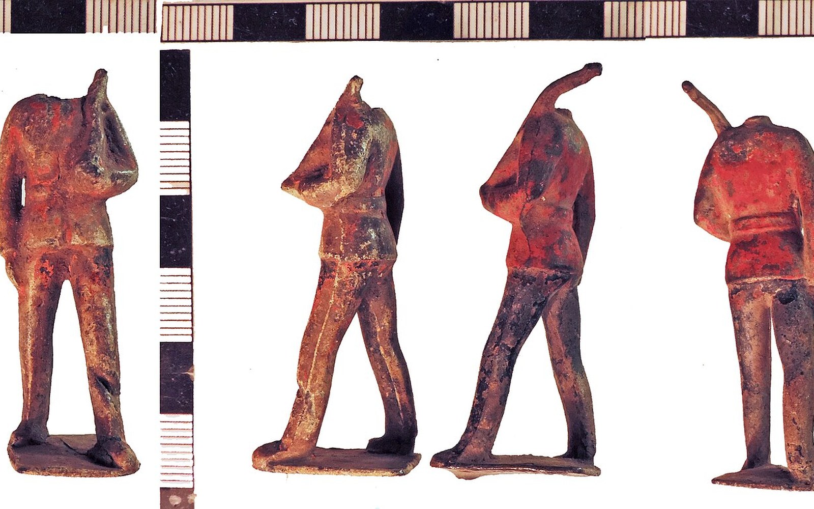 Four headless hollow-cast lead toy soldiers shown from different angles beside a measuring scale