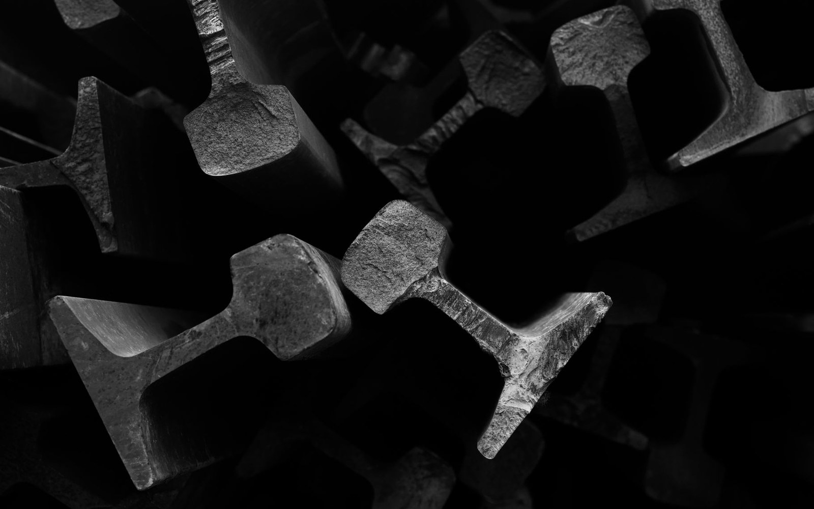 Close-up of stacked steel rail sections showing their cross-sections in dim light