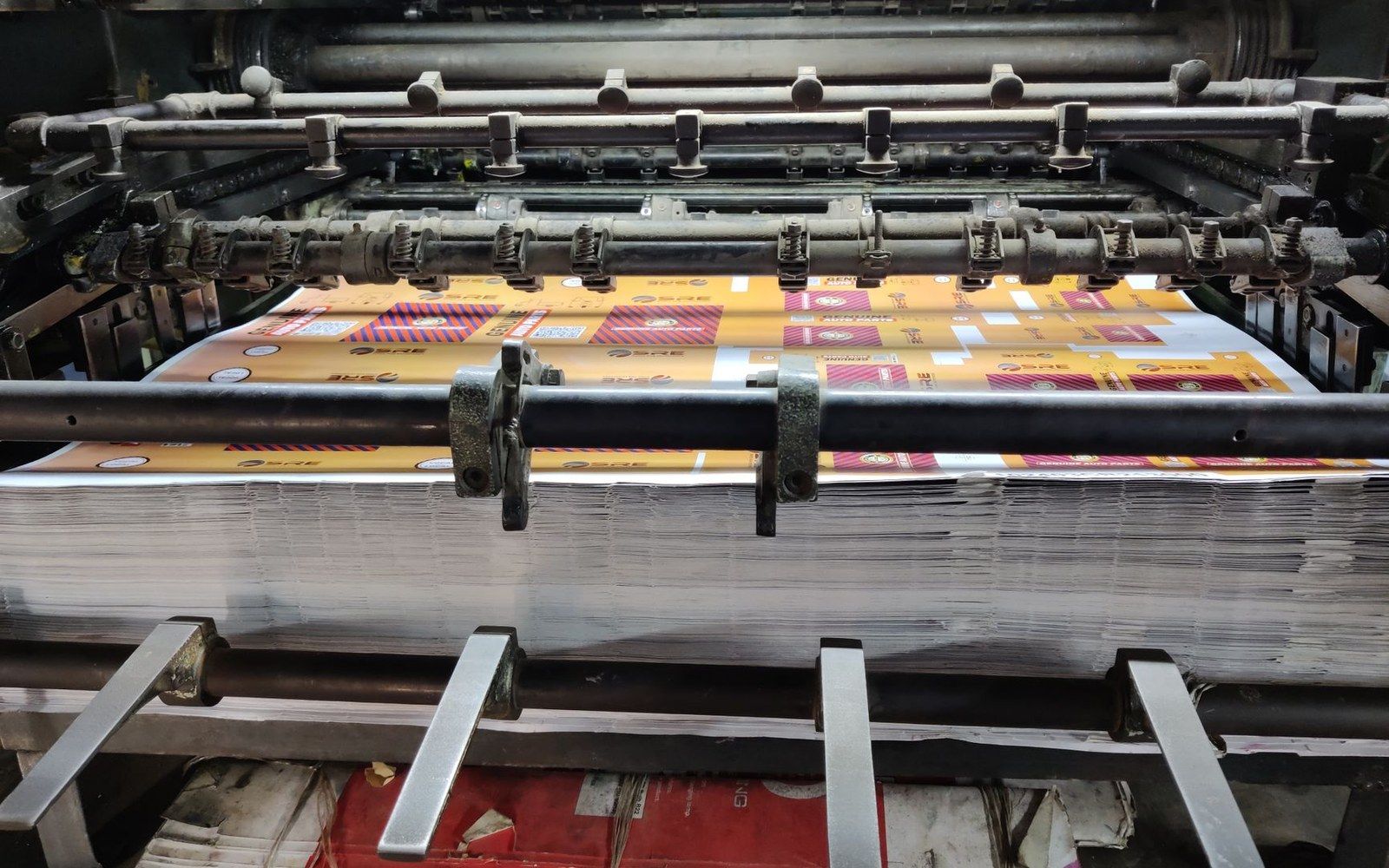 Printed metal sheets feeding through rollers on an industrial lithography press